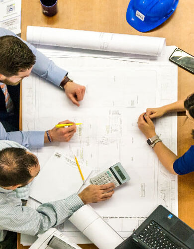 group of employees working on blueprints for construction project